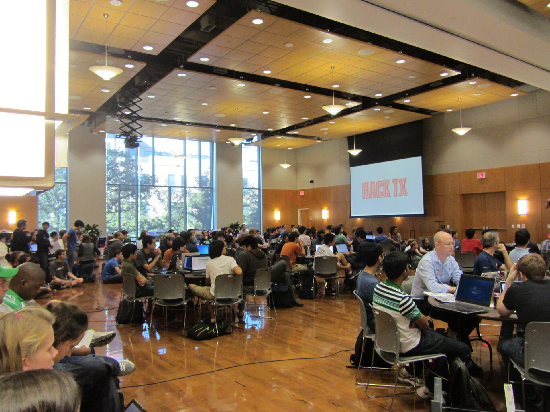 Hundreds of developers working on laptops at a HackTX hackathon in a large hall